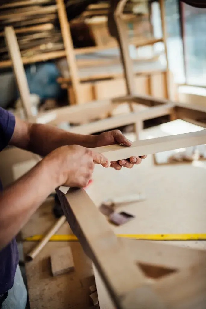Vakman werkt aan een houten meubelonderdeel op de fabrieksvloer